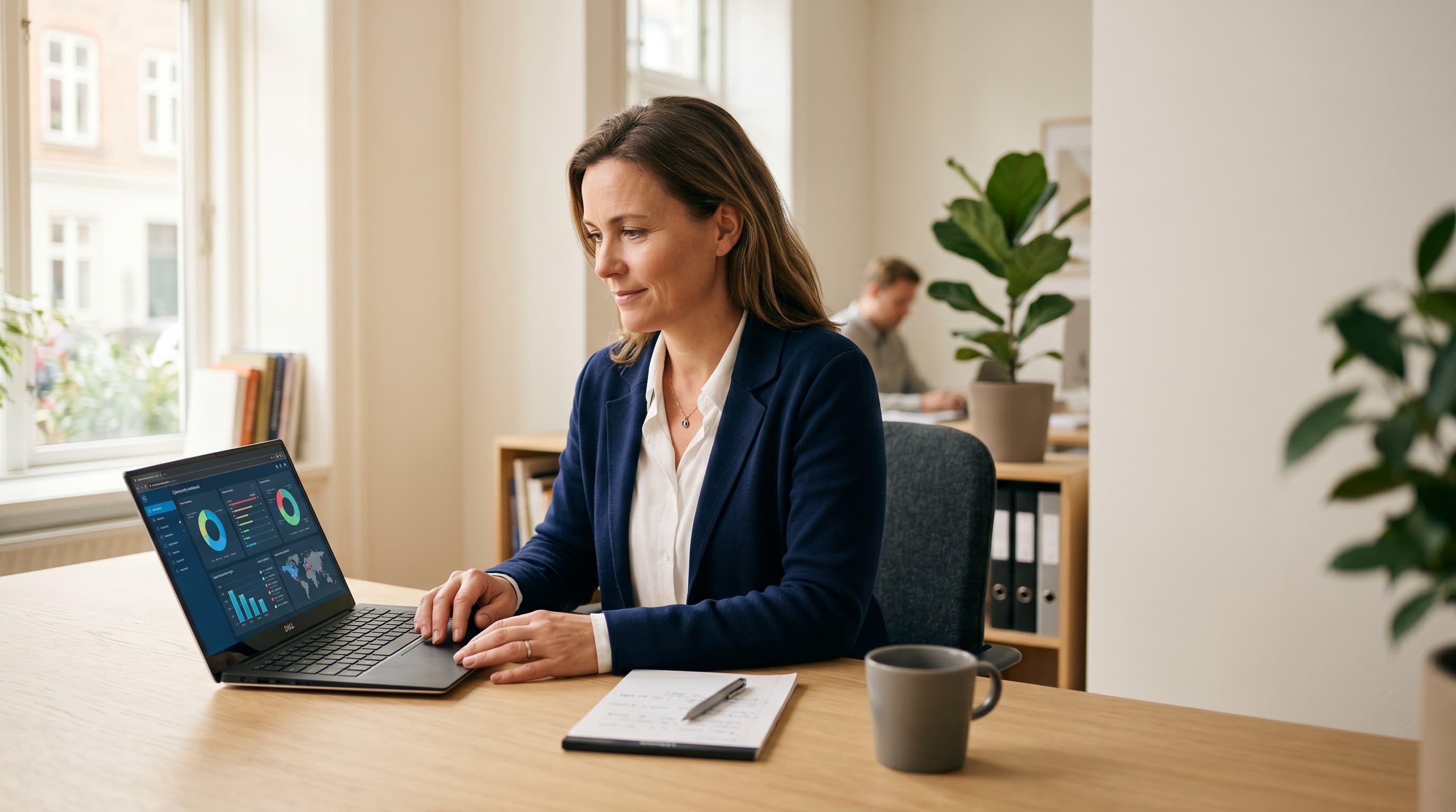 Small-business owner reviewing a cybersecurity dashboard on a laptop in a bright modern office